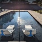 Two lounge chairs under umbrella in pool