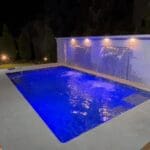 Backyard illuminated pool with wall waterfalls